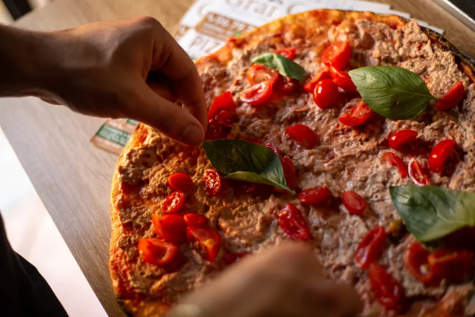 Il basilico posato a mano su una pizza appena sfornata