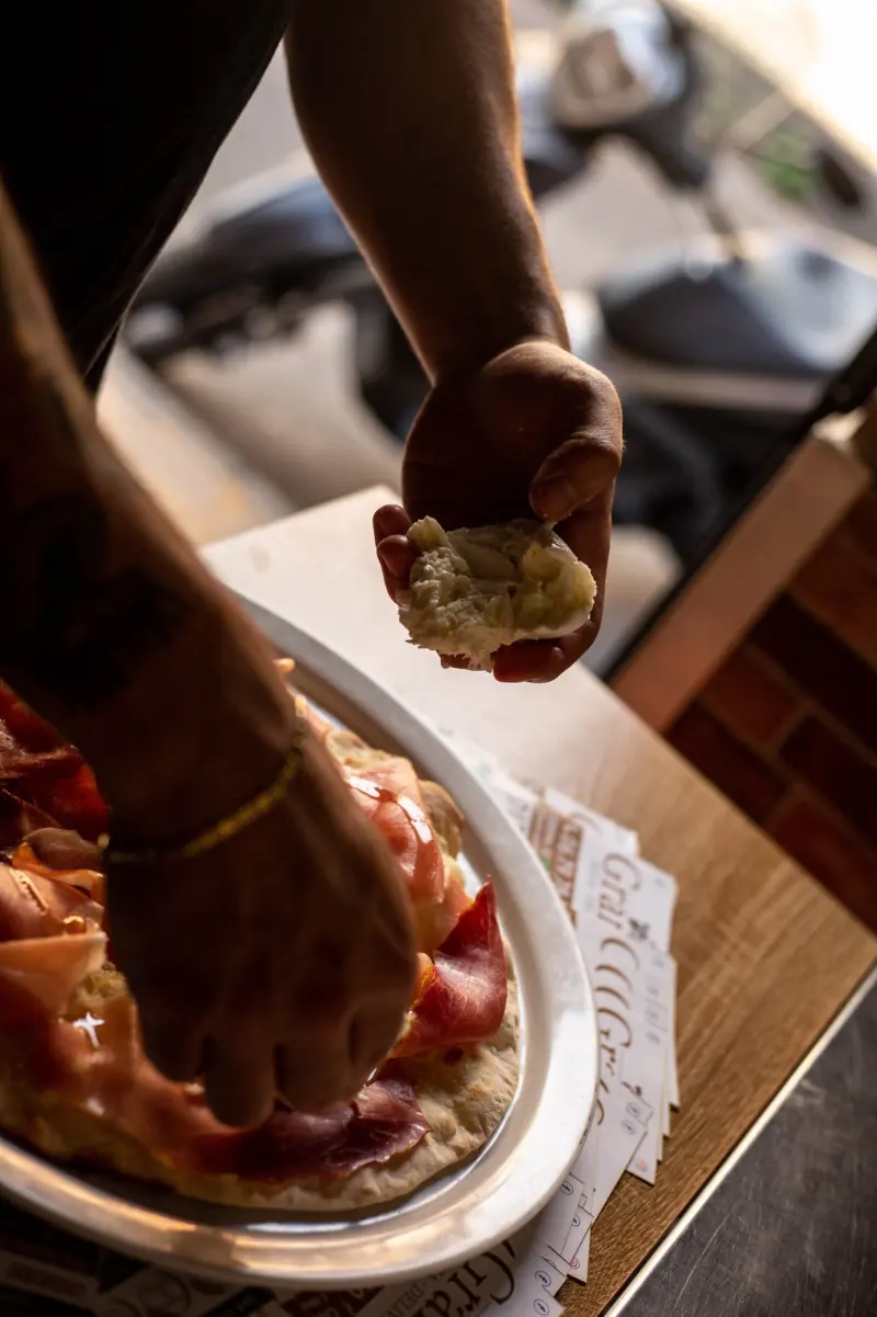 Una mano prende un pezzo di pizza bianca dal vassoio
