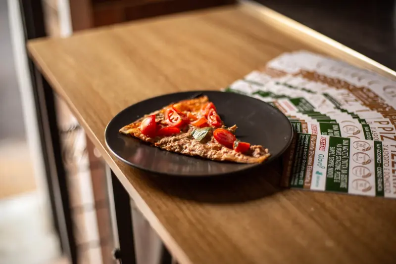 Una fetta di pizza con pomodorini sul bancone di legno